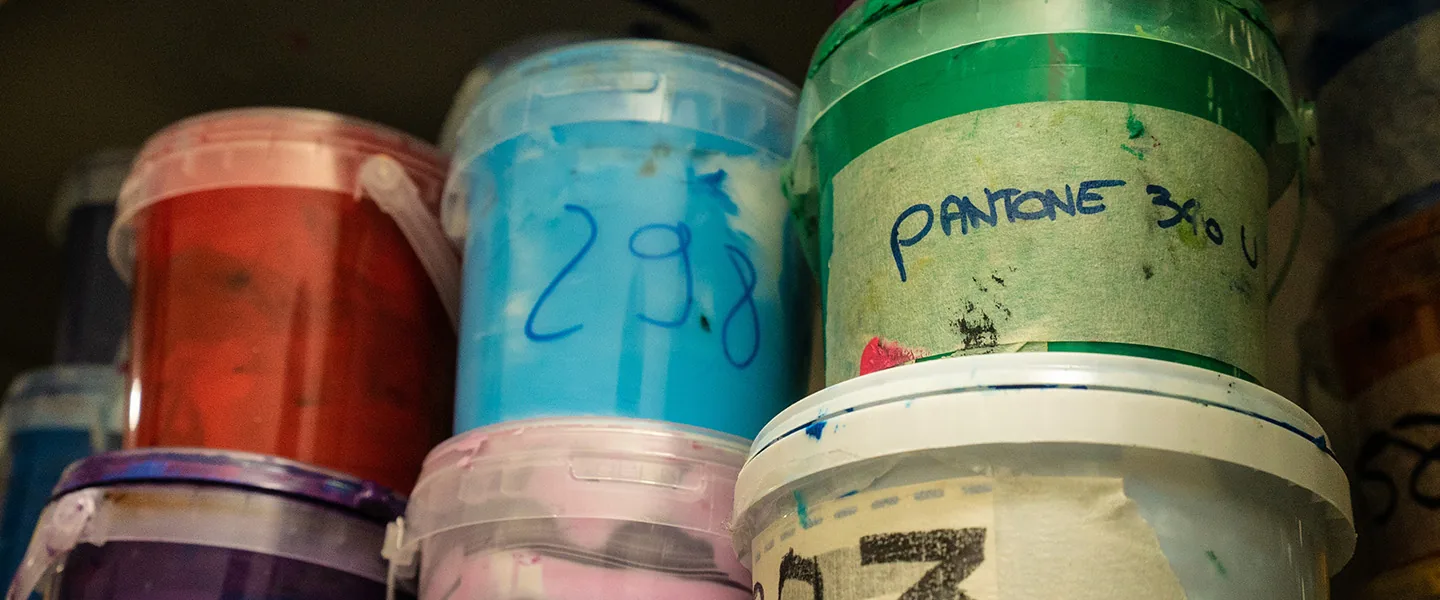 Pots d’encre de sérigraphie colorés empilés sur une étagère de l’atelier