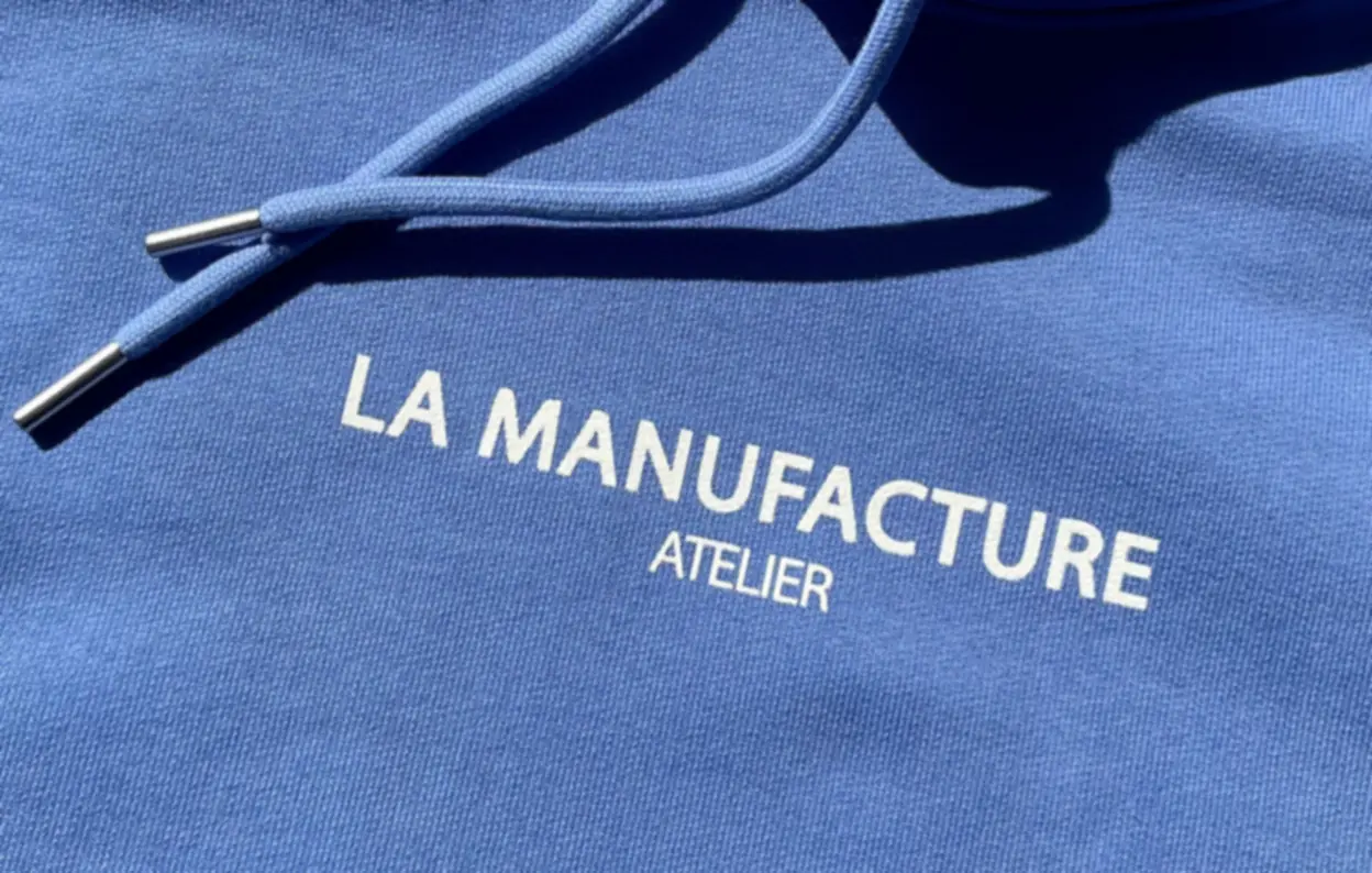 Gros plan d’un sweat à capuche bleu imprimé La Manufacture Atelier