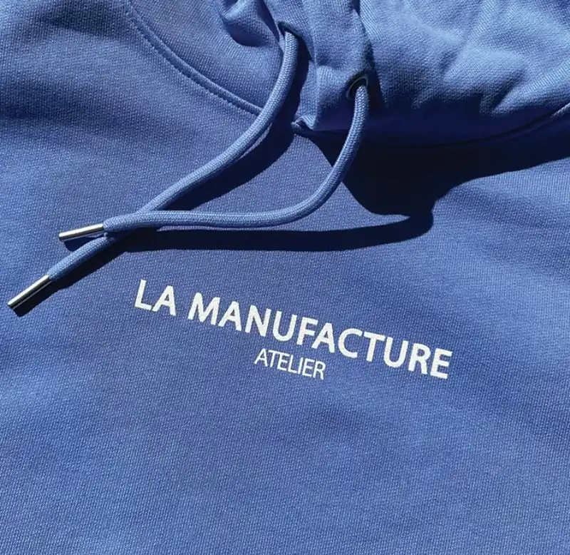 Gros plan d’un sweat à capuche bleu imprimé La Manufacture Atelier